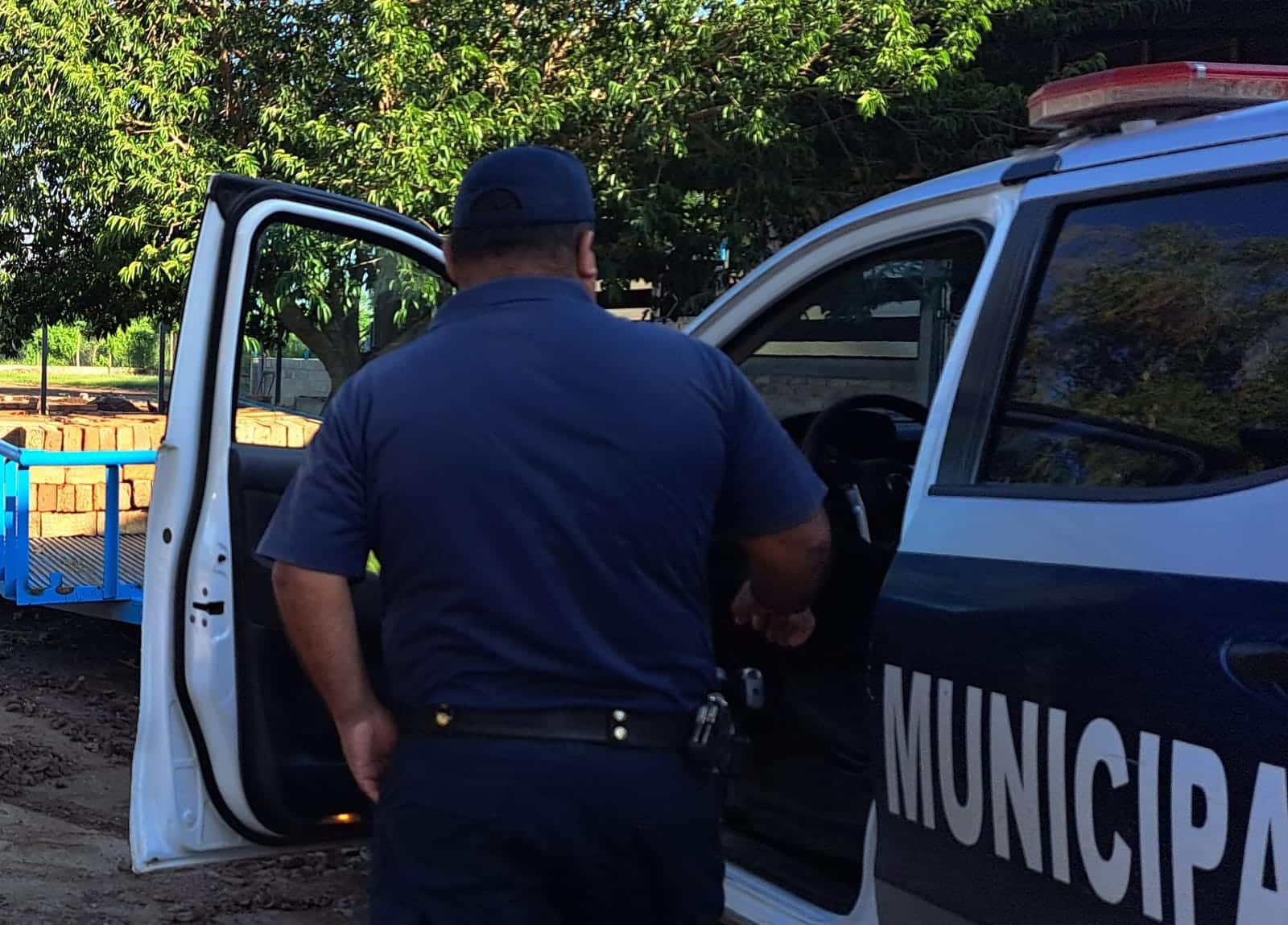 Policía con la puerta abierta de una patrulla de Guasave