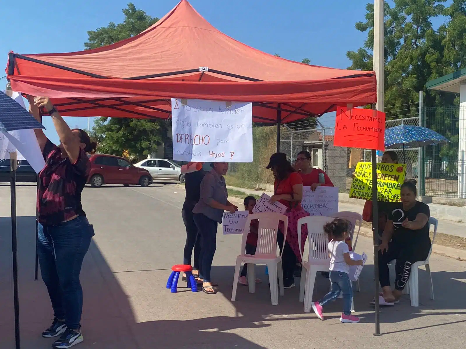 Mujeres bajo una carpa afuera de un kínder en Los Mochis