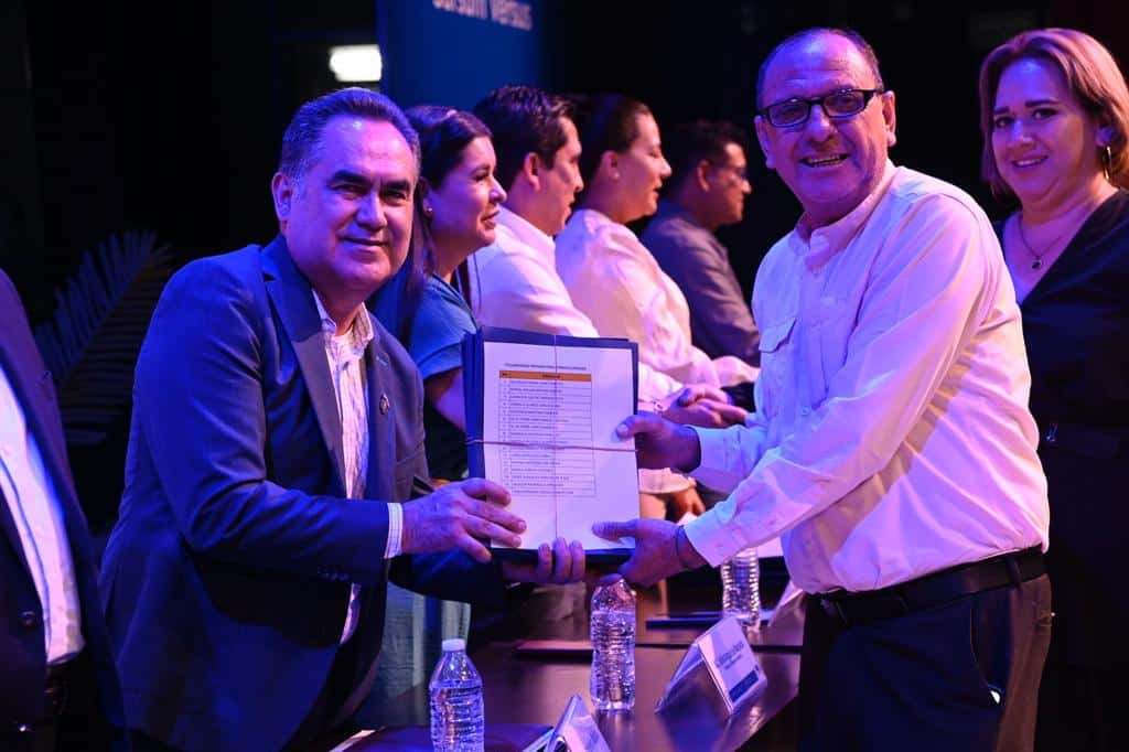 Rector de la UAS con docente recibiendo base
