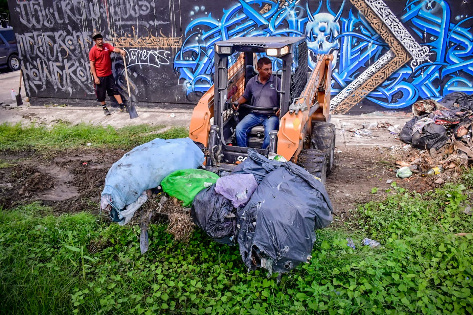 Personal del ayuntamiento realizando limpieza con retroexcavadora.