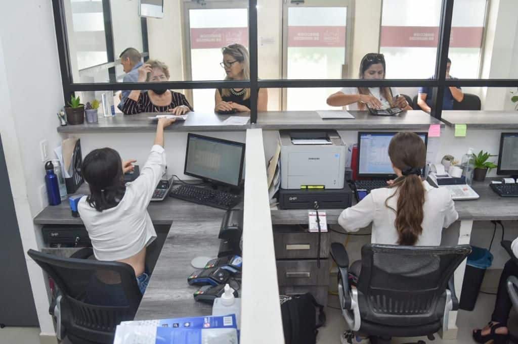 Personas pagando en unas instalaciones y otras sentadas