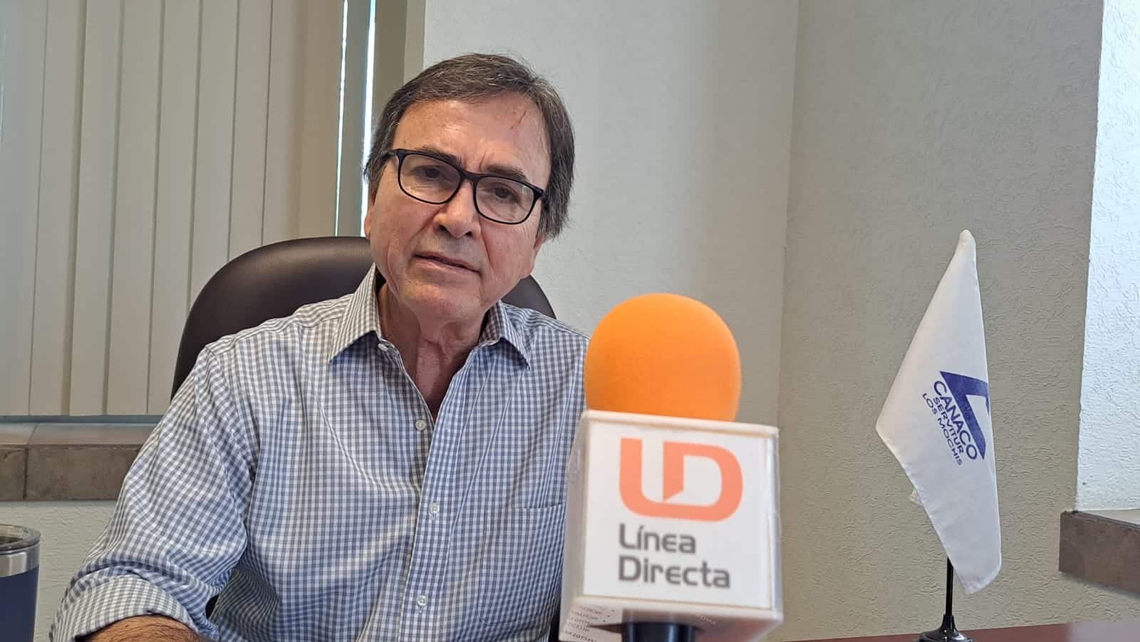 Una persona de lentes sentada y un micrófono de LD