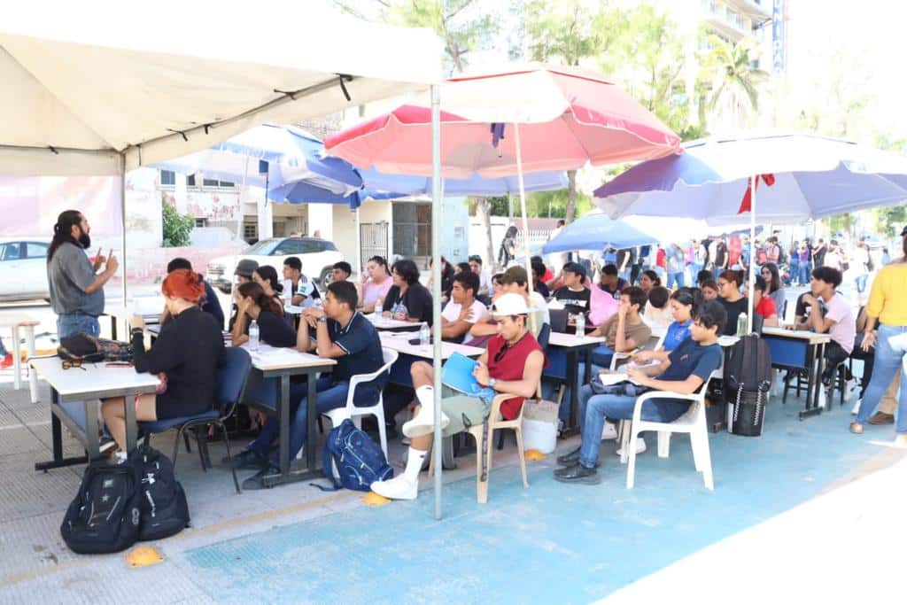 Alumnos tomando clases a las afueras de la escuela
