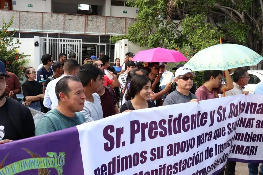 Maestros y alumnos de Facimar sosteniendo pancartas durante su manifestación a las afueras de Semarnat