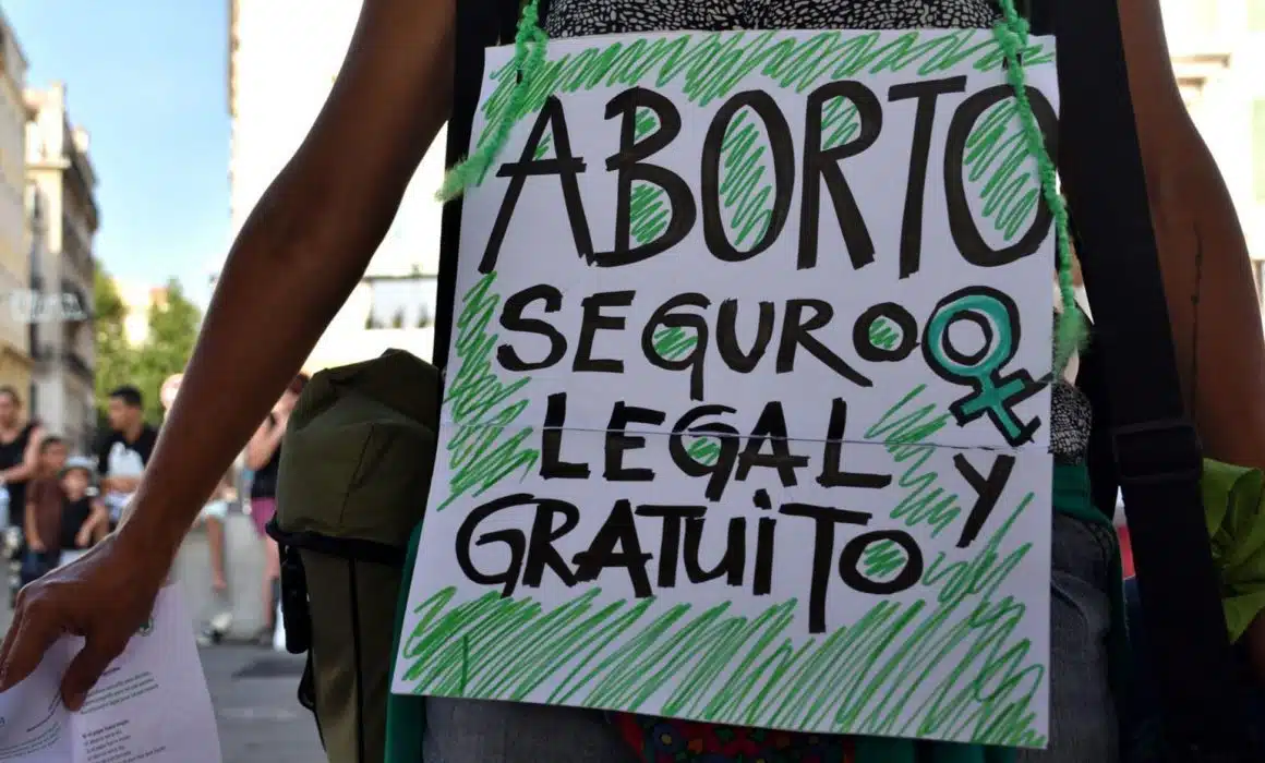 Mujer con cartel de aborto seguro y legal en México