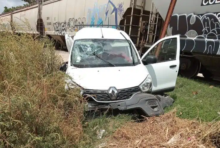 Camioneta Renault Kangoo, blanca, es envestida por tren.