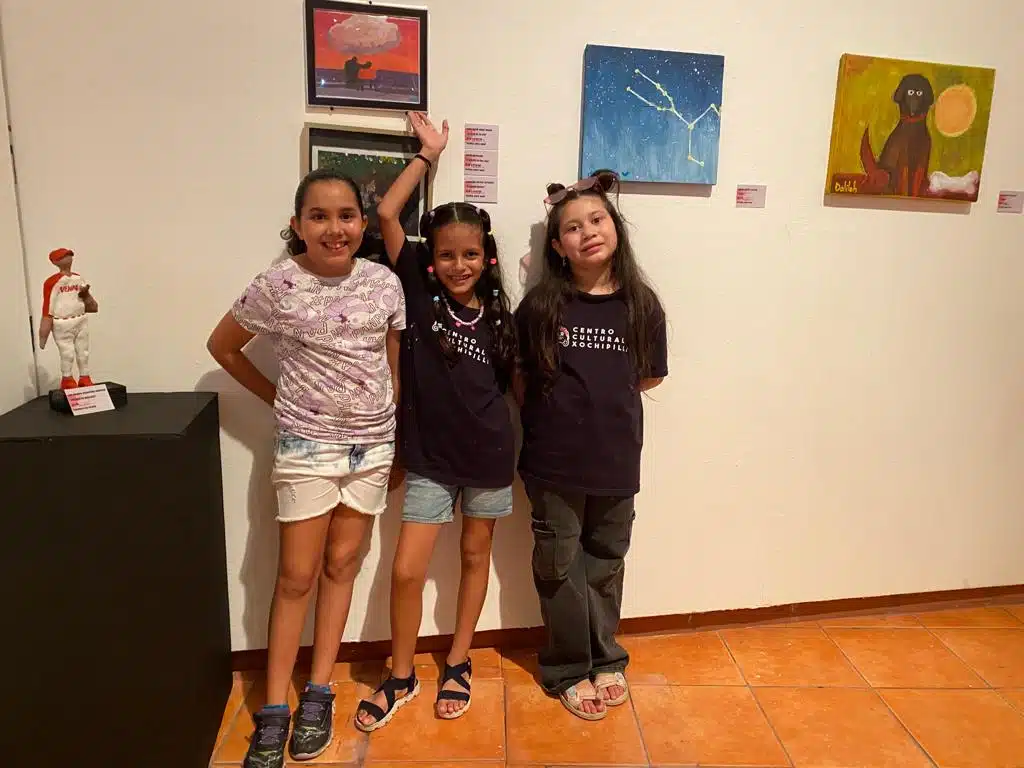 Niñas posando junto a sus obras de arte