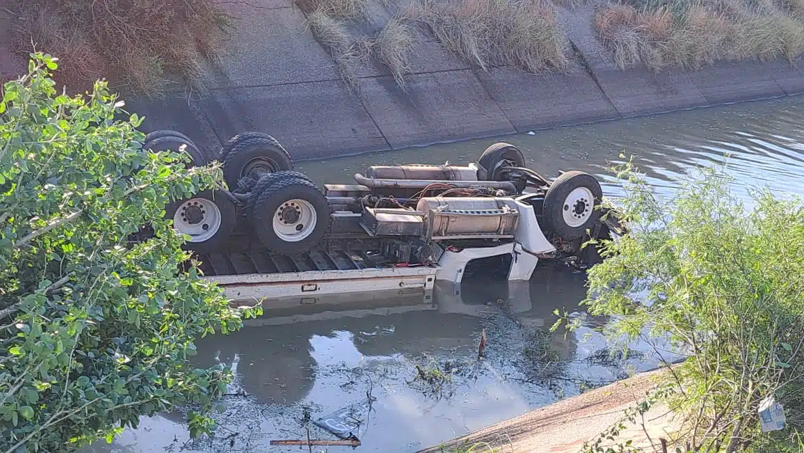 Camión de volteo con las llantas hacia arriba al interior de un canal