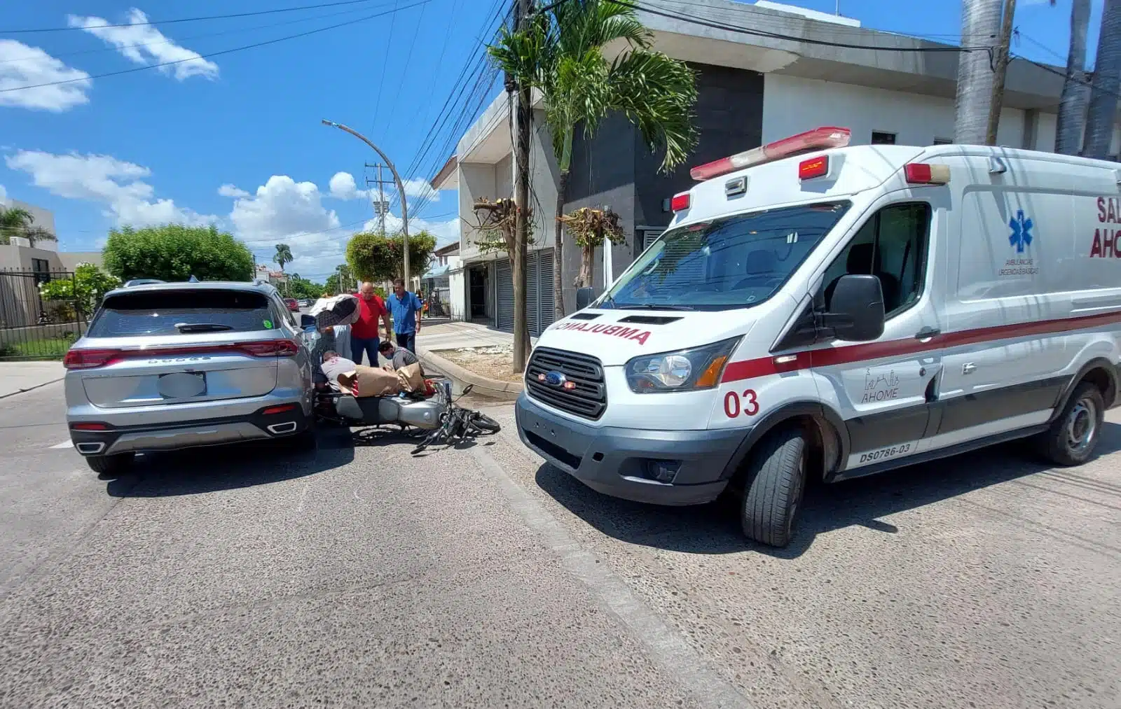 Socorristas y testigos auxiliando al joven motociclista. Hay una ambulancia, la motocicleta se encuentra tirada y la camioneta se encuentra detenida