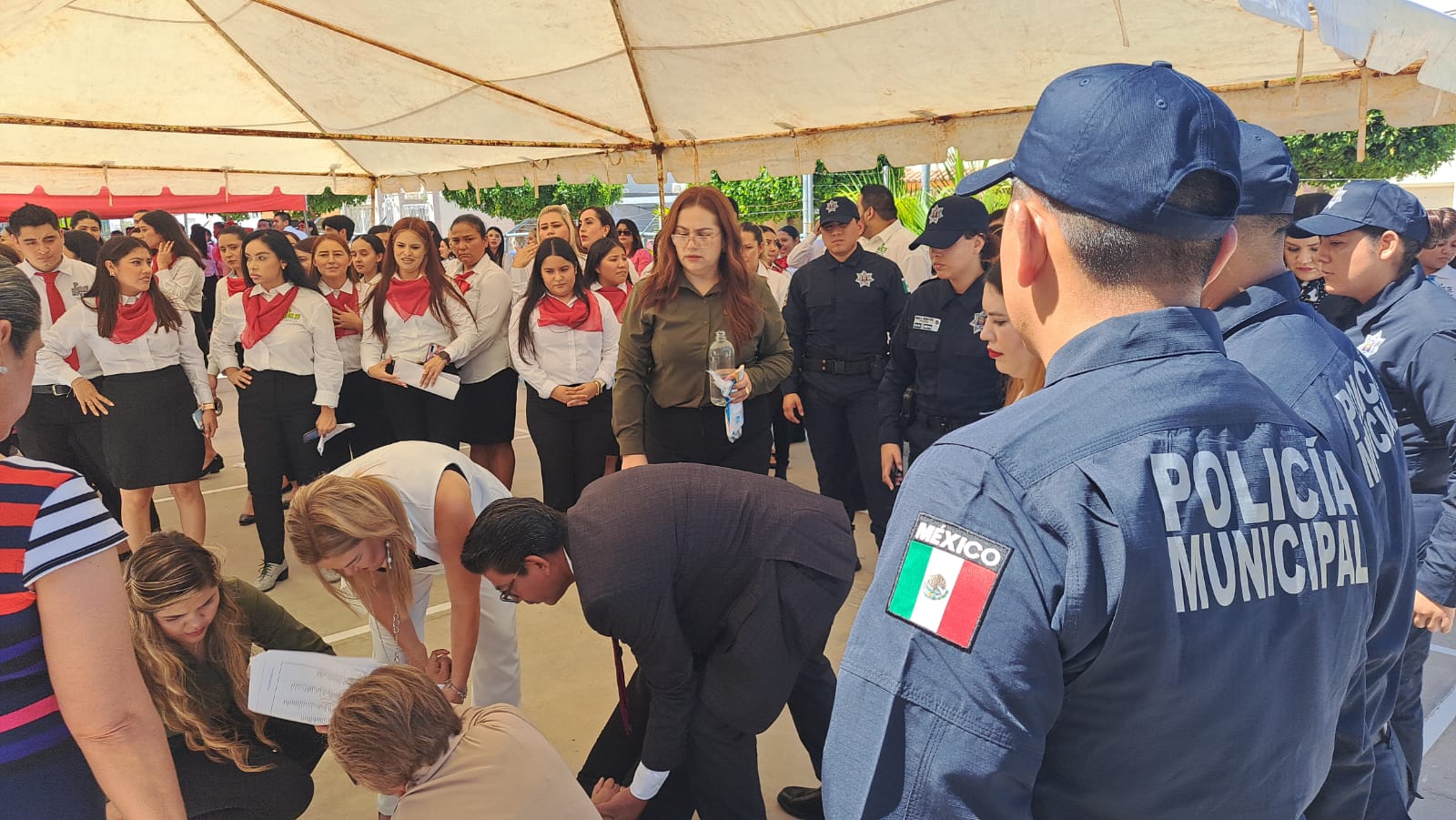 JOVEN DESMAYADA Y ALREDEDOR DE ELLA DOCENTES Y ELEMENTOS DE LA POLICÍA MUNICIPAL.