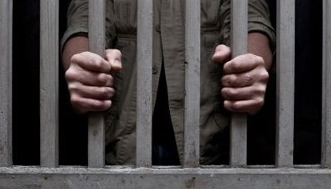 Hombre tras las rejas de una celda de prisión