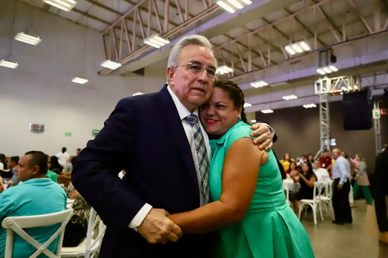 Gobernador Rubén Rocha Moya abrazando fraternalmente a una trabajadora en el evento