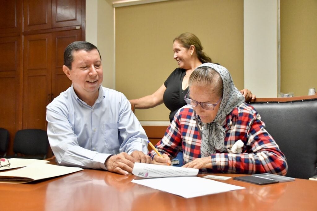 Martín Camacho Figueroa junto a una de las viudas firmando su nómina