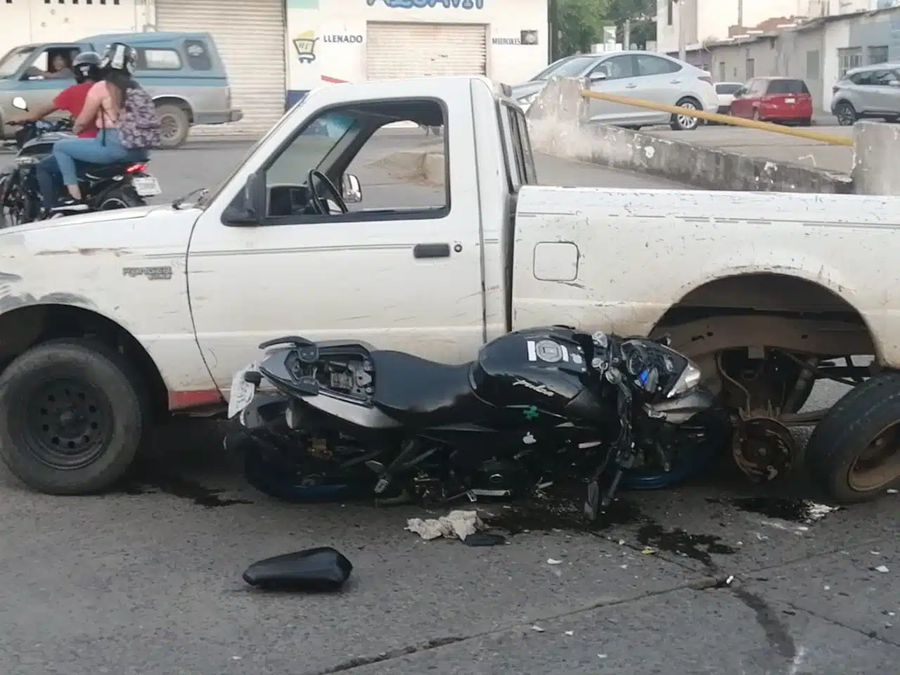 Motocicleta Pulsar atascada debajo de una camioneta Ford Ranger