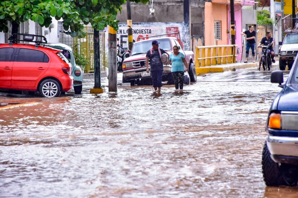 Personas caminando a través de una calle inundada