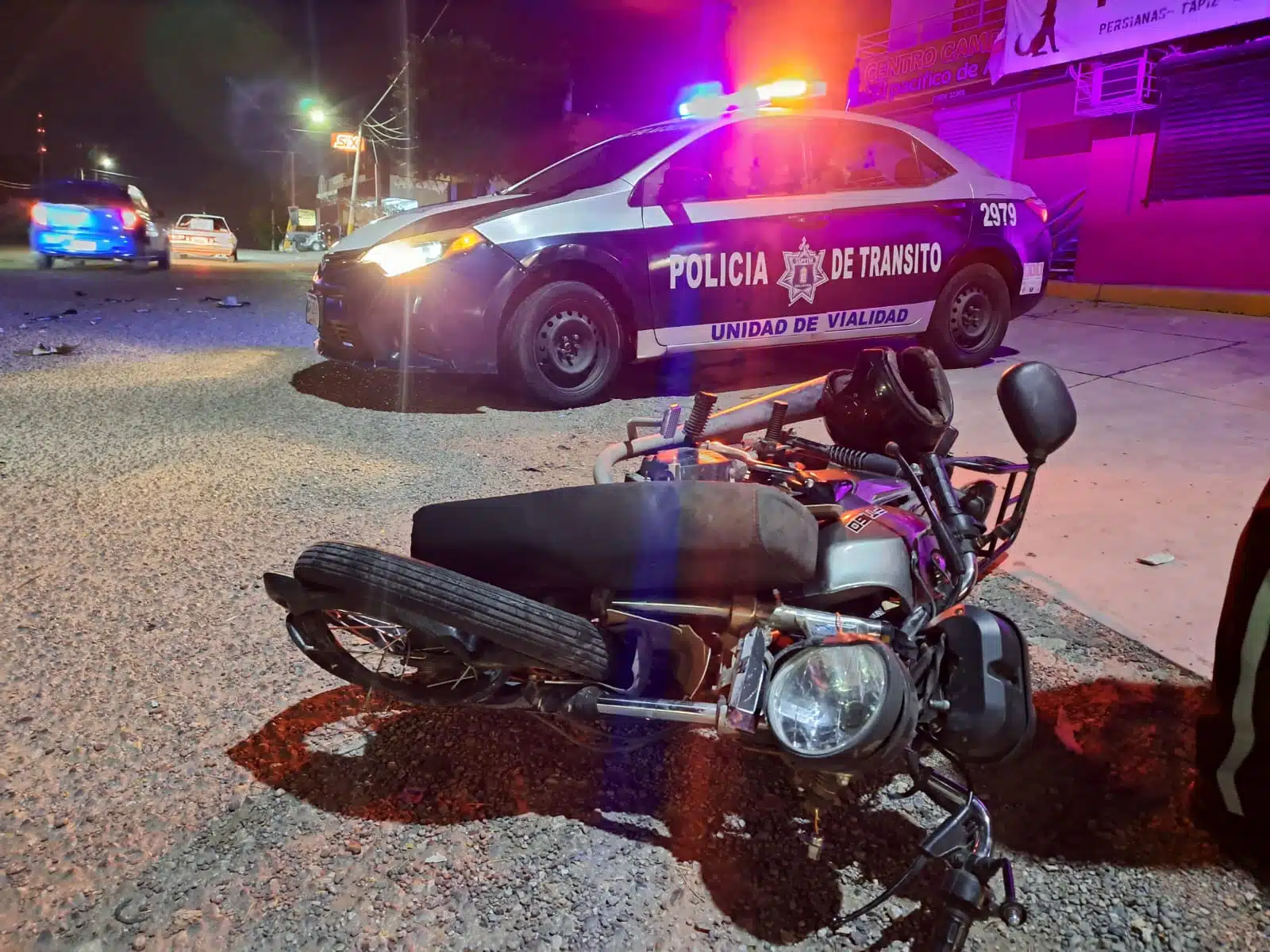 Moto tirada en el pavimento junto a una unidad de Tránsito