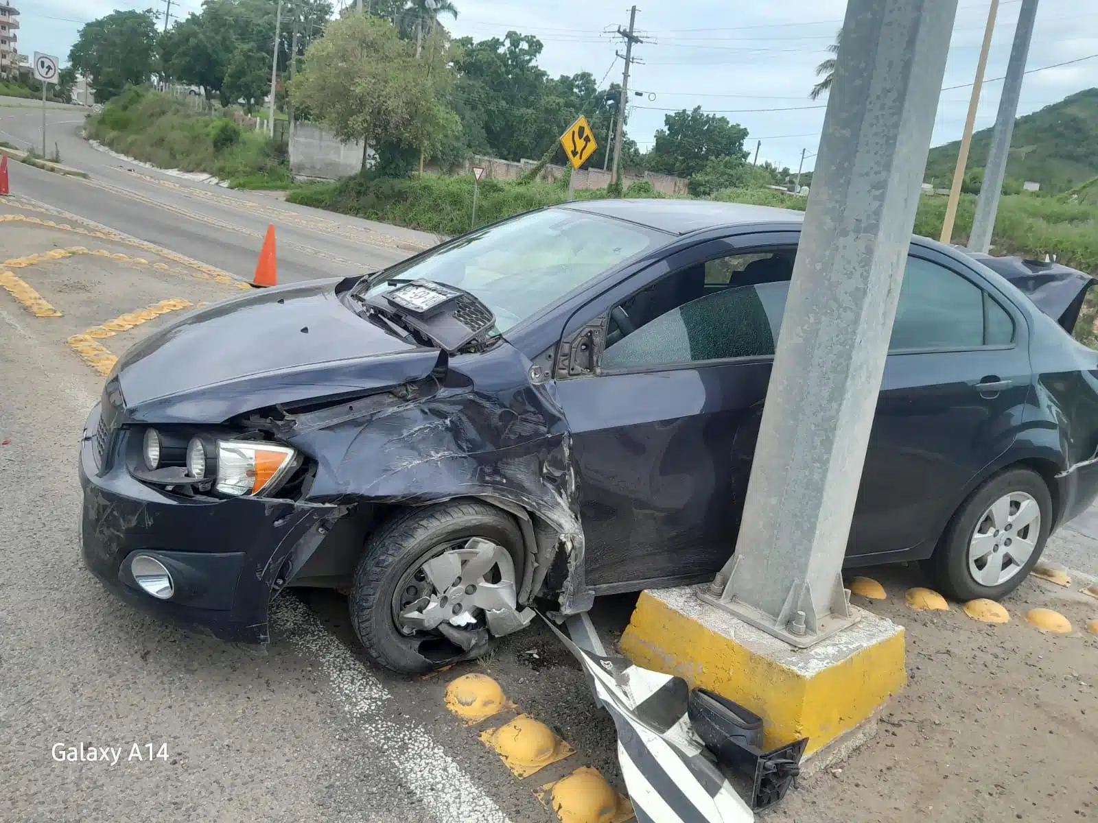 Vehículo Chevrolet Sonic impactado contra un poste y con daños en la carrocería