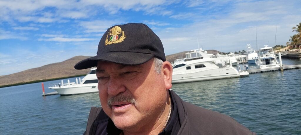 Una persona con gorra y al fondo barcos y agua de mar