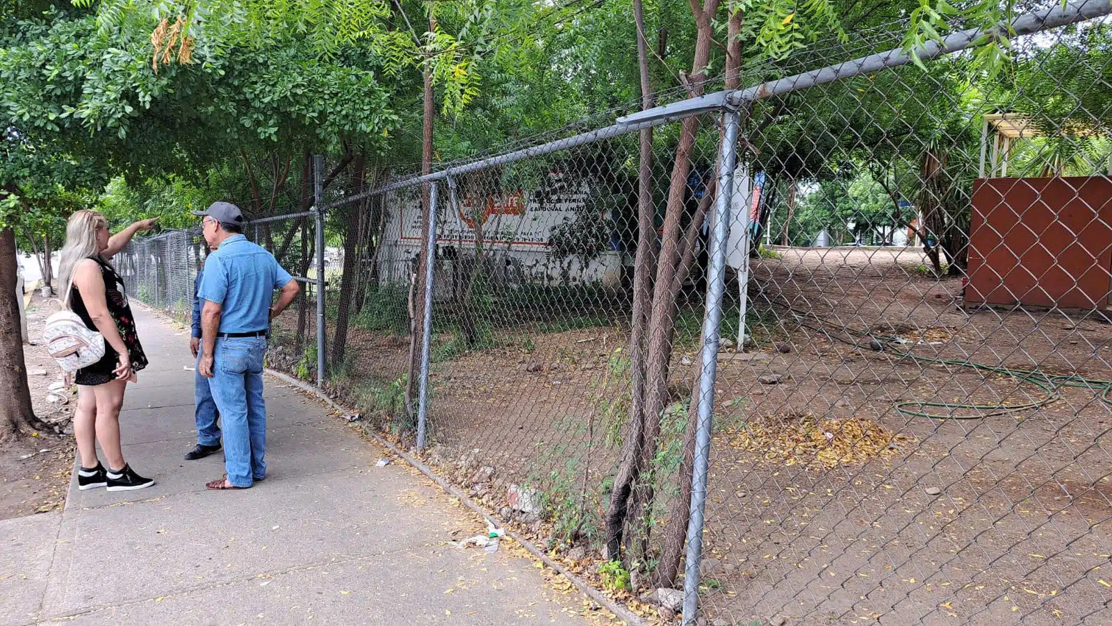 Parte de afuera de escuela y al fondo padres de familia