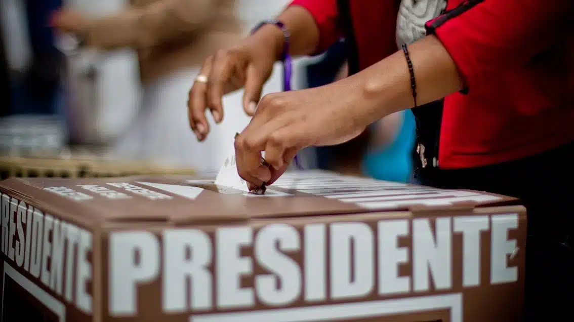 Persona introduciendo su voto en la urna presidencial