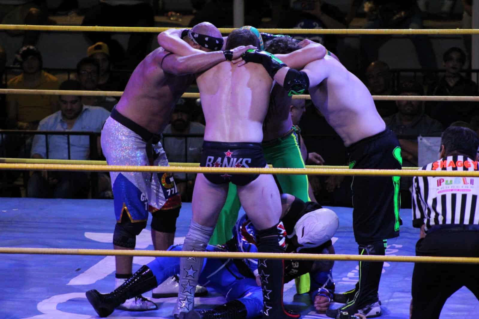 Luchadores del bando rudo sometiendo a un técnico