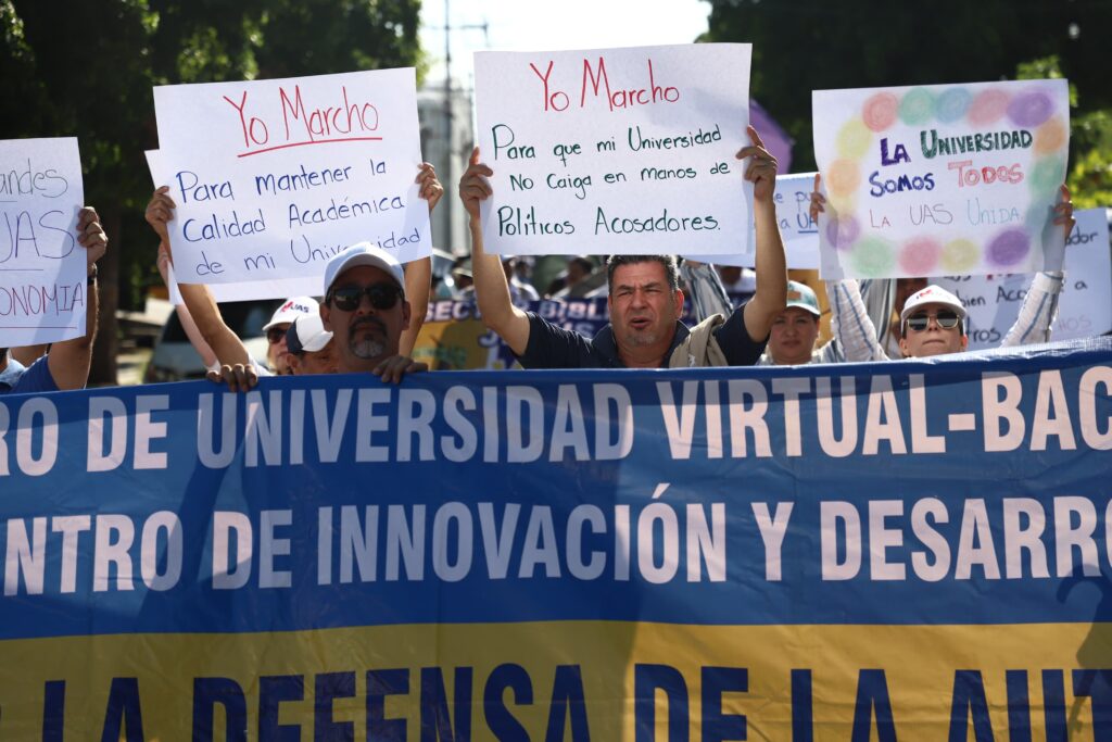 Estudiantes y maestros de la UAS con una pancarta enfrente marchando en Culiacán