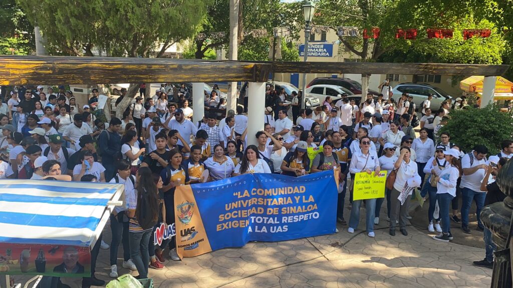 Estudiantes y maestros de la UAS con una pancarta enfrente marchando en Guasave