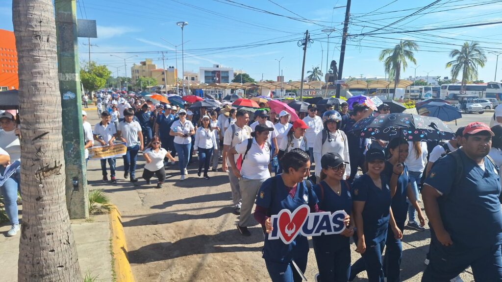 Estudiantes y maestros de la UAS con una pancarta enfrente marchando en Mazatlán