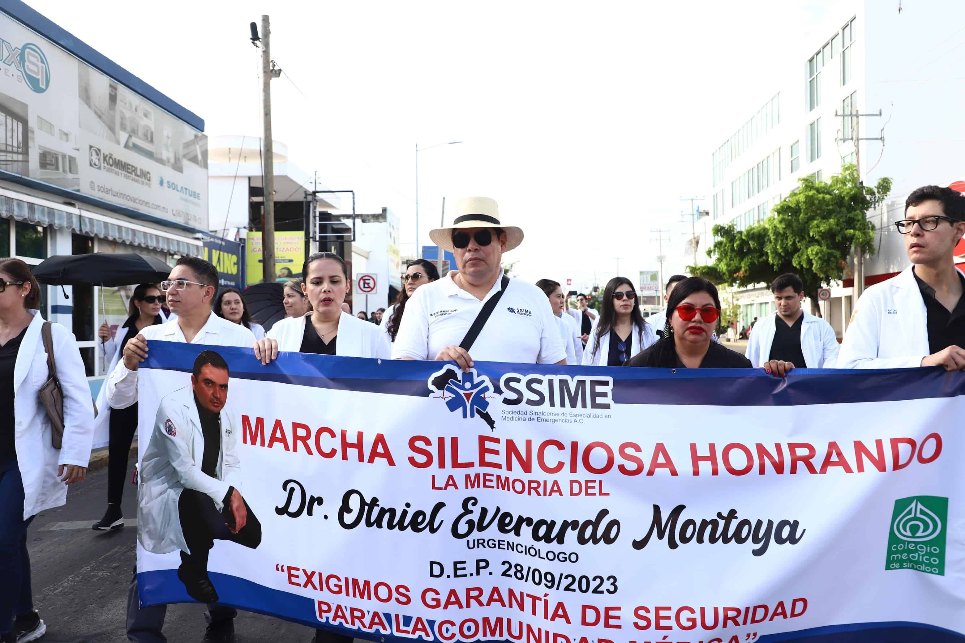 Personas vestidas de blanco con cubrebocas y una lona