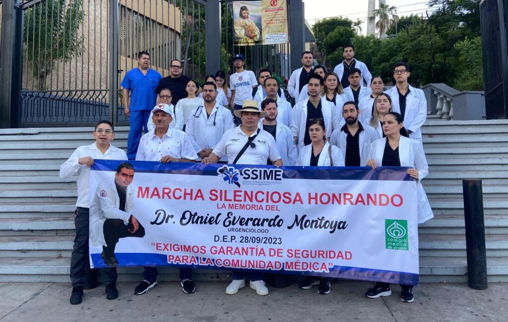 Personas vestidas de blanco con cubrebocas y una lona