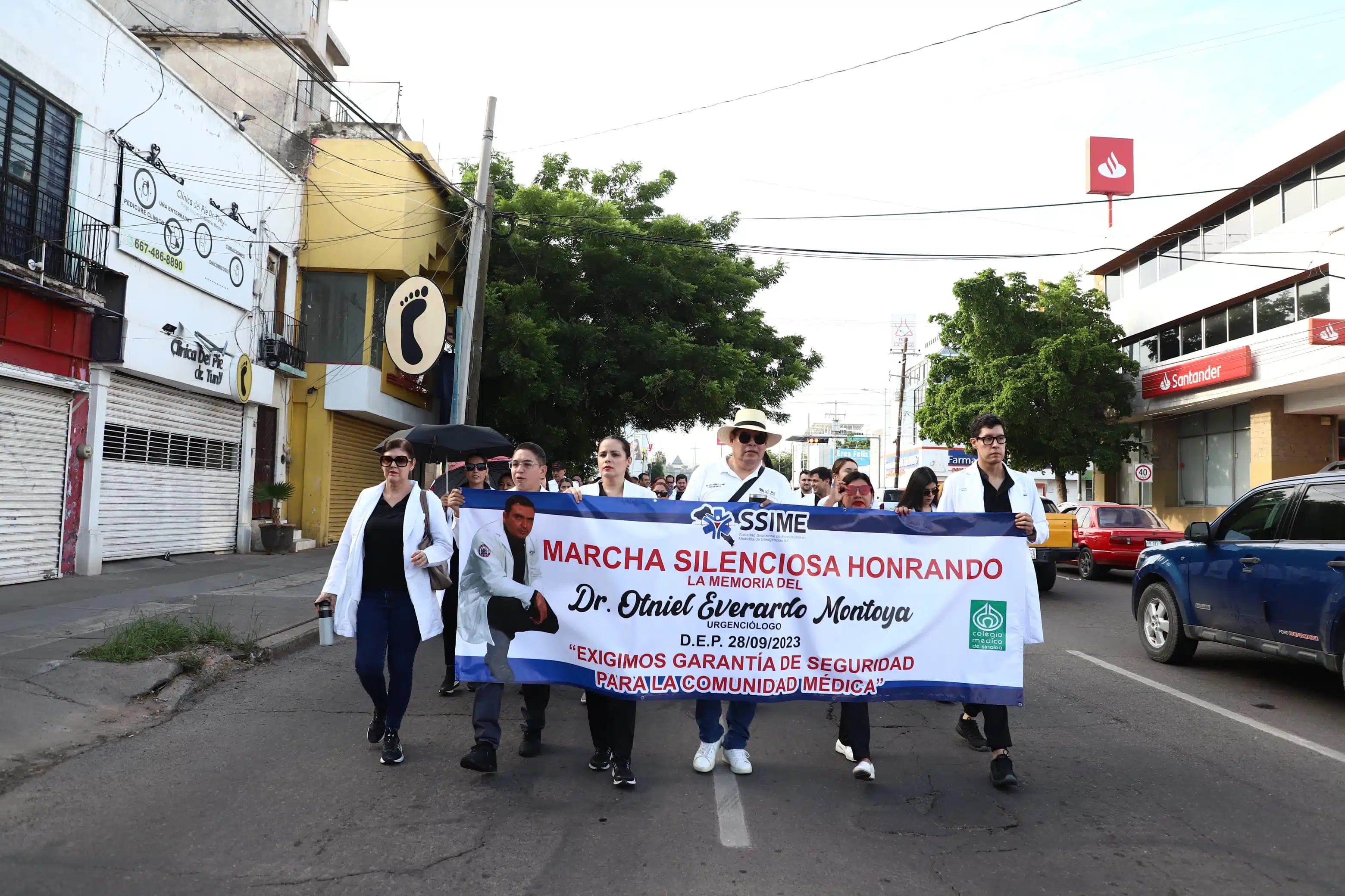 Personas vestidas de blanco con cubrebocas y una lona