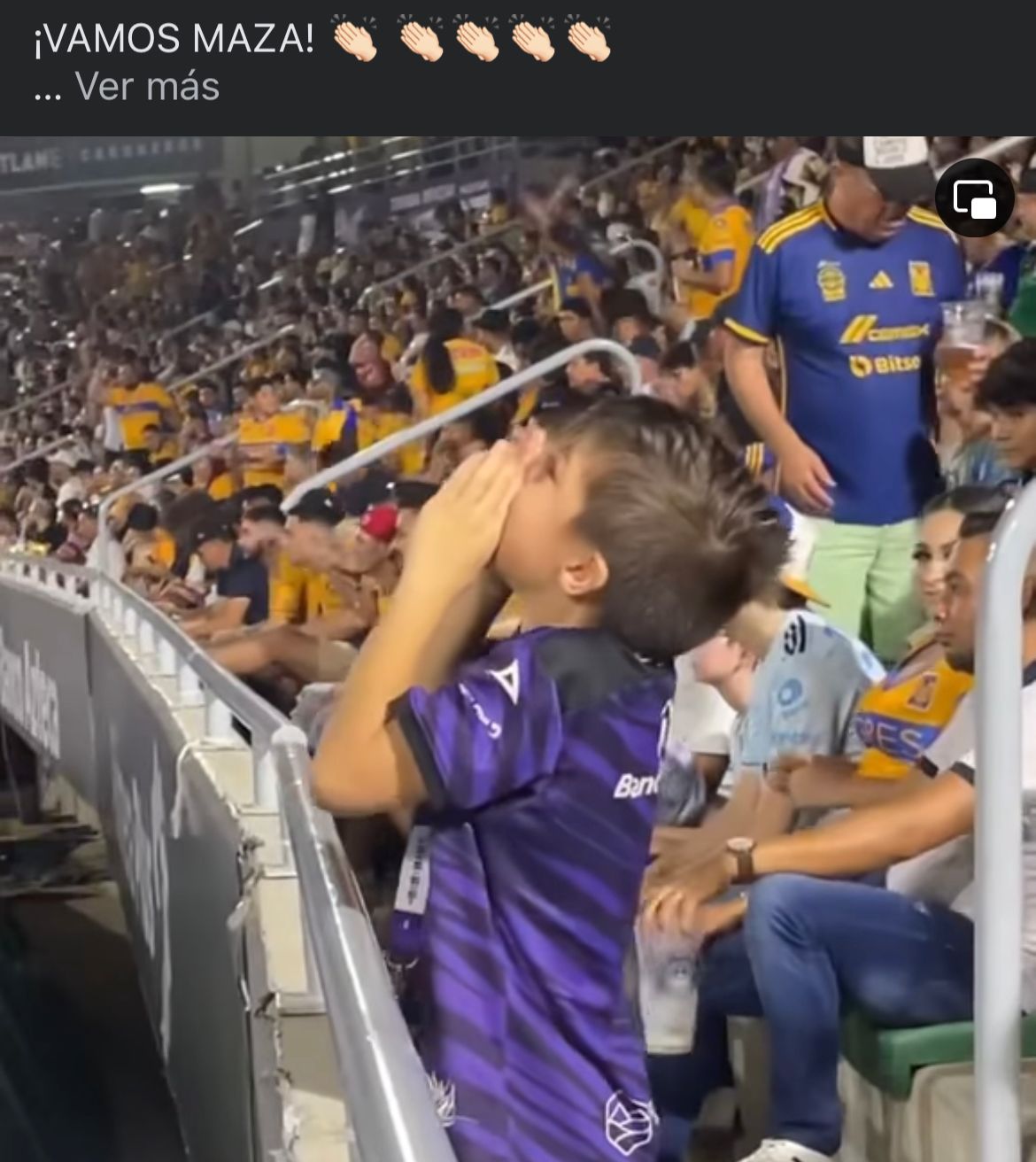Un niño con playera morada de un equipo de futbol y aficionados con playeras de color amarillo mostaza