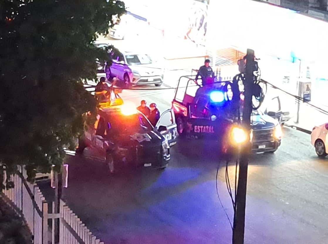 Personas arriba de dos patrullas de la policía Estatal