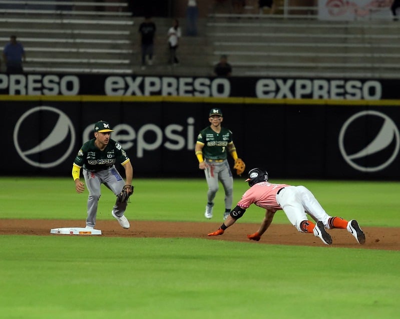Jugada en segunda base donde se barre de cabeza José Cardona, mientras que Isaac Rodríguez espera tiro a la intermedia