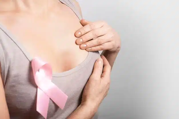Mujer tocándose un seno en revisión del cáncer de mama