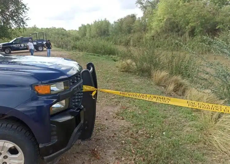 Camioneta de la policía con una cinta amarilla delimitando el área del crimen en un campo.