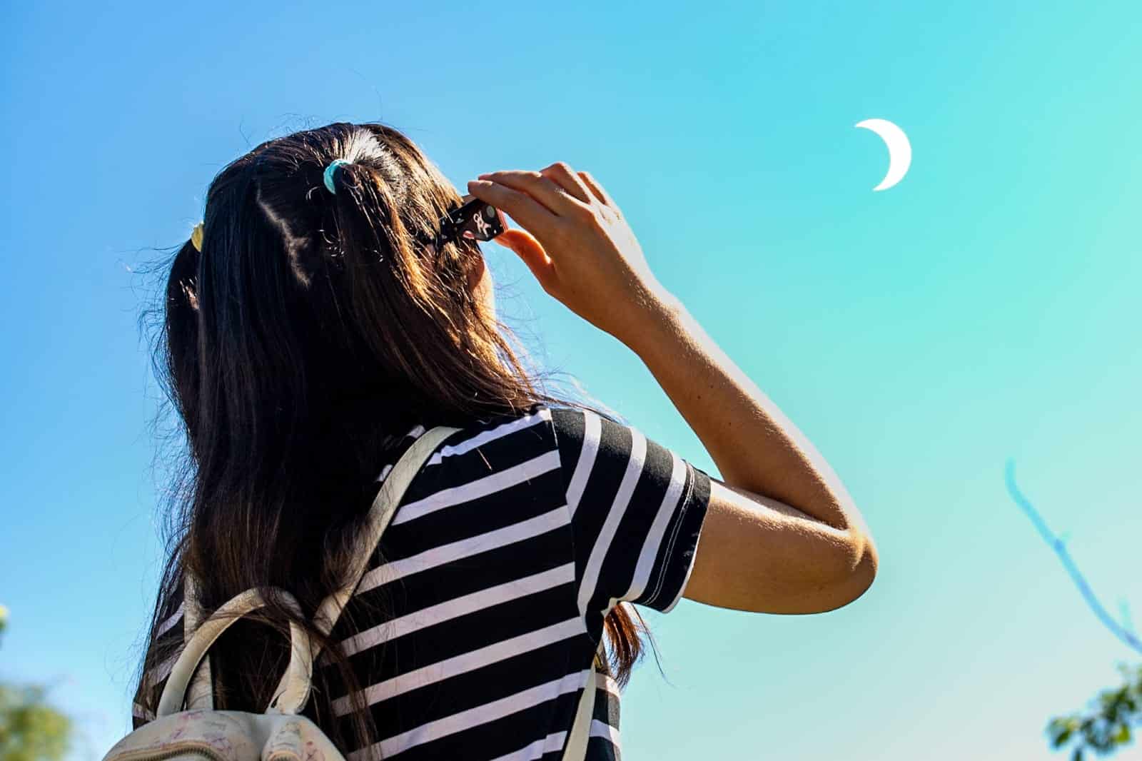 Joven apreciando el eclipse parcial de sol con gafas especiales
