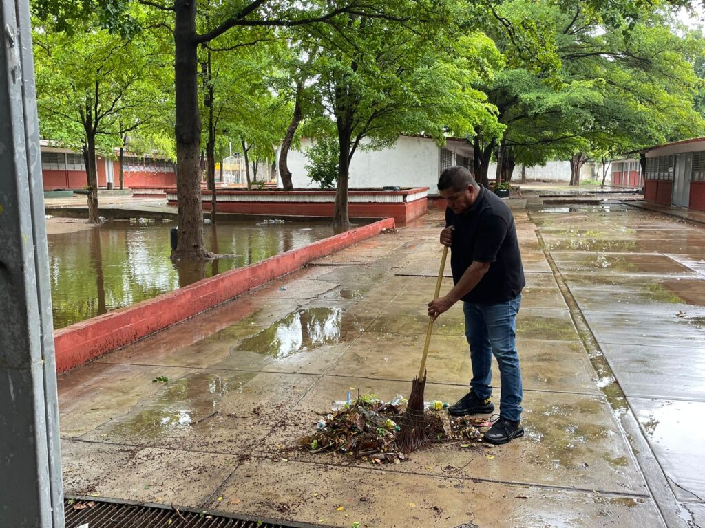 Persona limpiando la basura en una escuela inundada