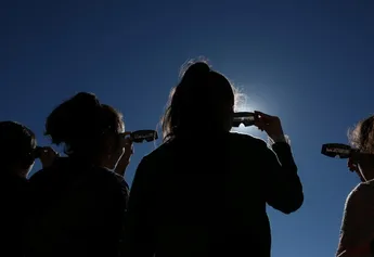 personas mirando hacía el cielo con lentes especiales para eclipse solar