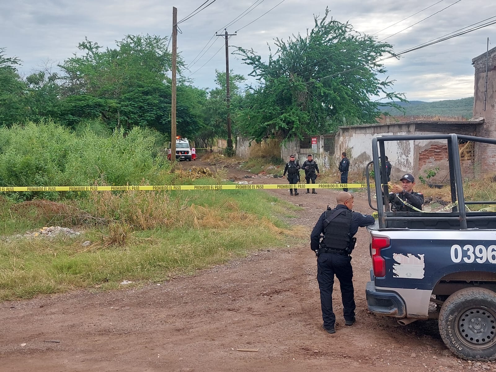 elementos de la policía municipal al fondo una cinta amarilla delimitando el area del hallazgo y a lo lejos una ambulancia