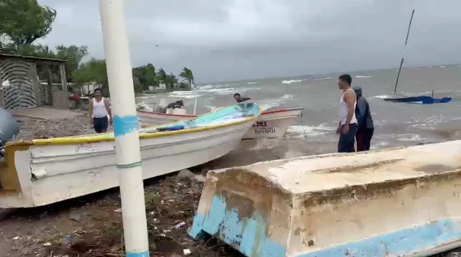 Pescadores resguardando botes por fuertes olas