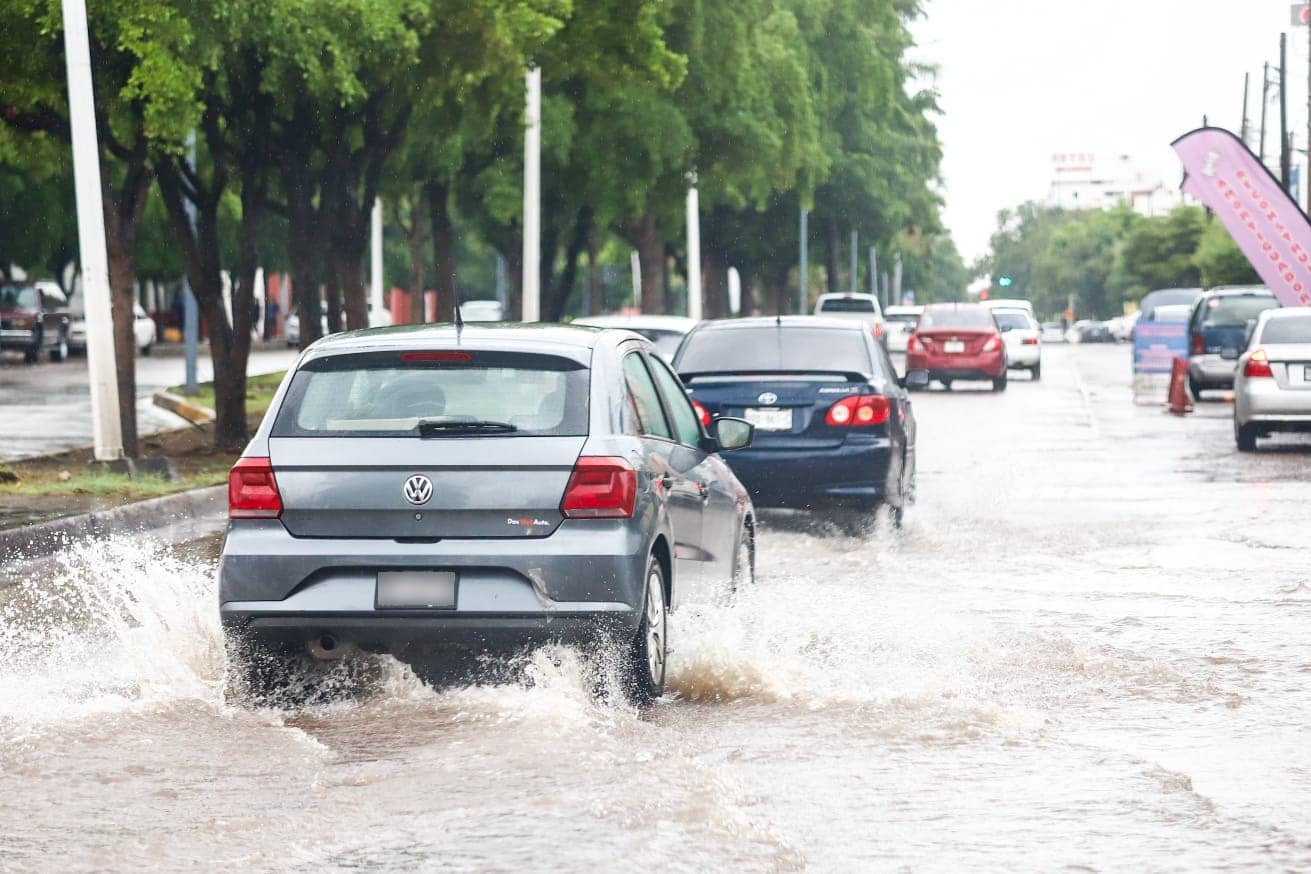 Carros cruzando por calle encharcada en Culiacán