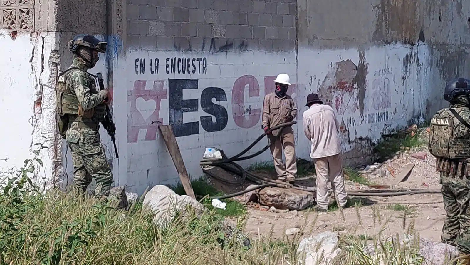 Personal de Pemex agarrando mangueras ; militares vigilan la zona