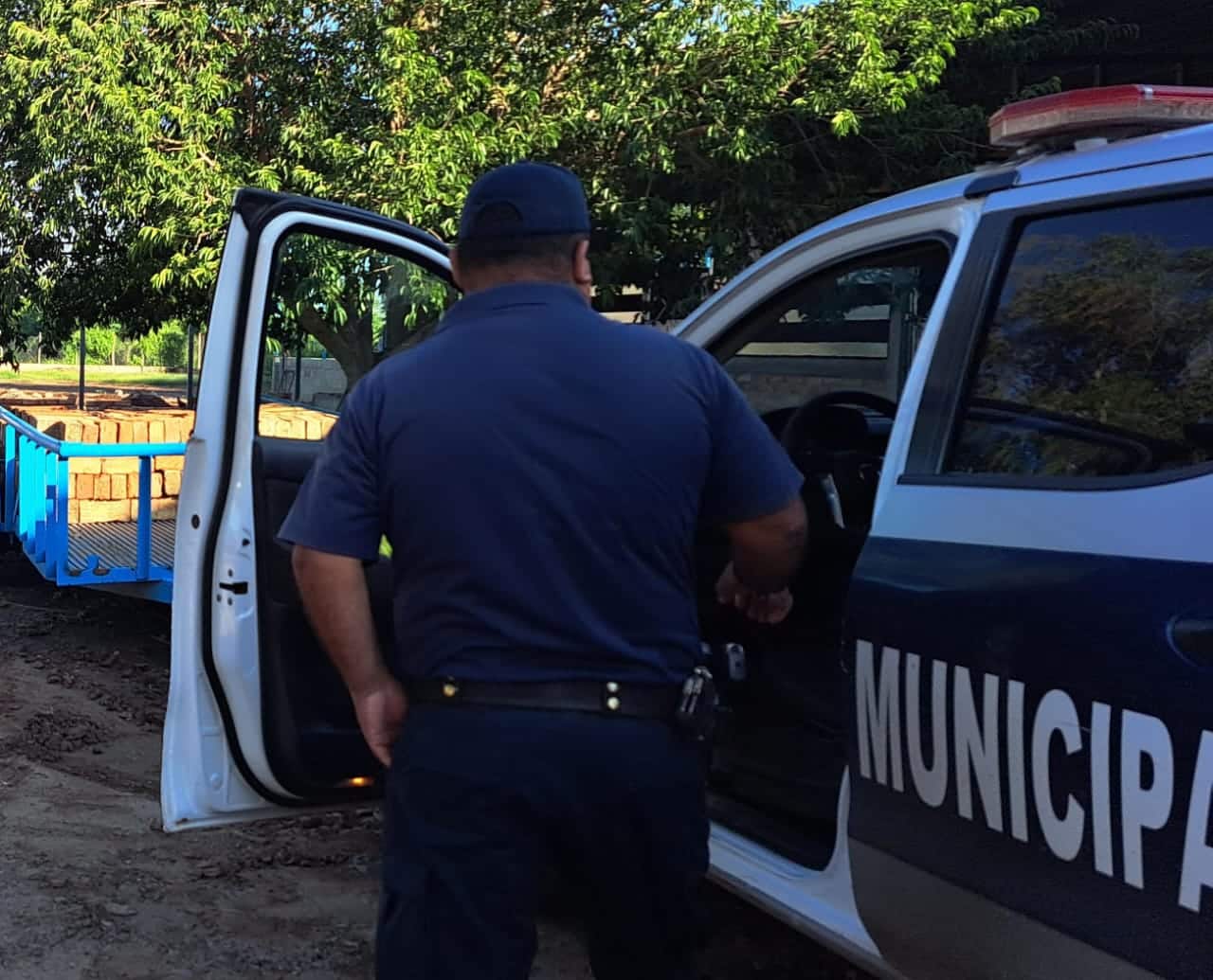 Policía de espalda subiendo a patrulla