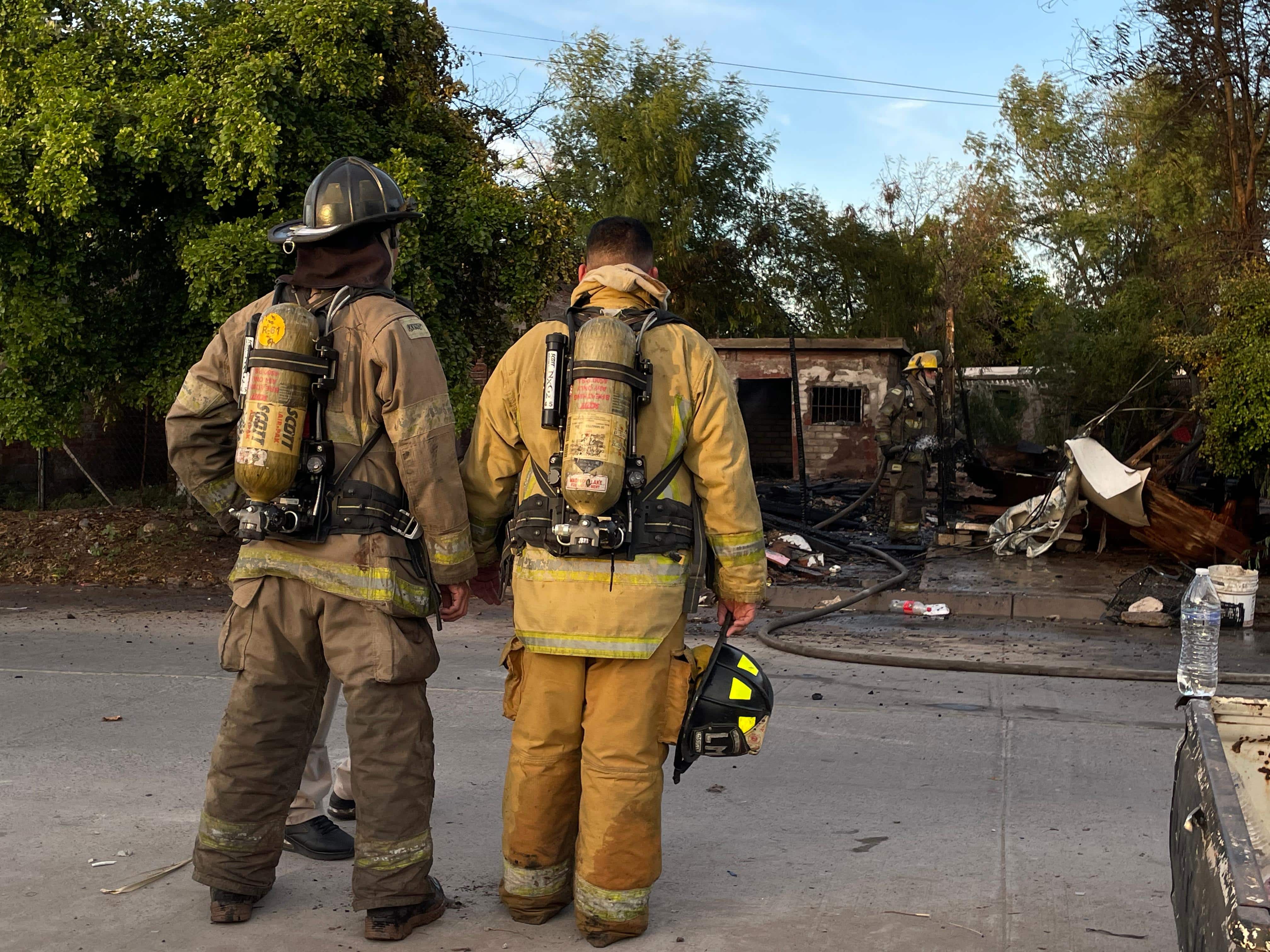 Personal de Bomberos de pie frente a la vivienda incendiada