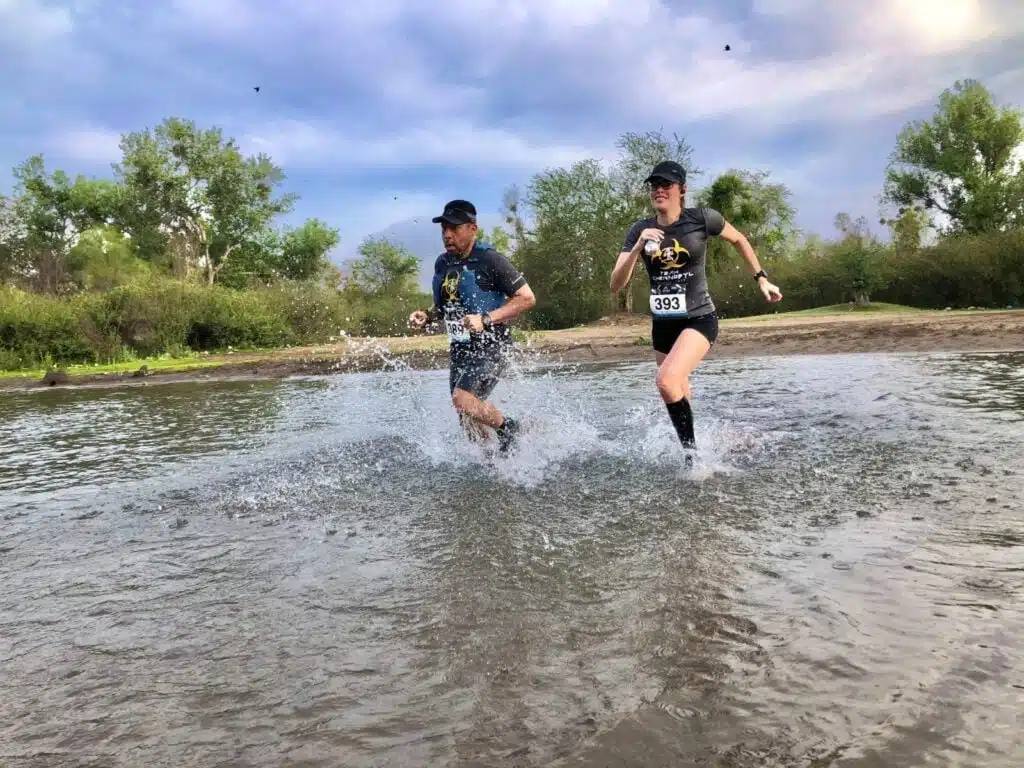 2 personas corriendo en las aguas de un río