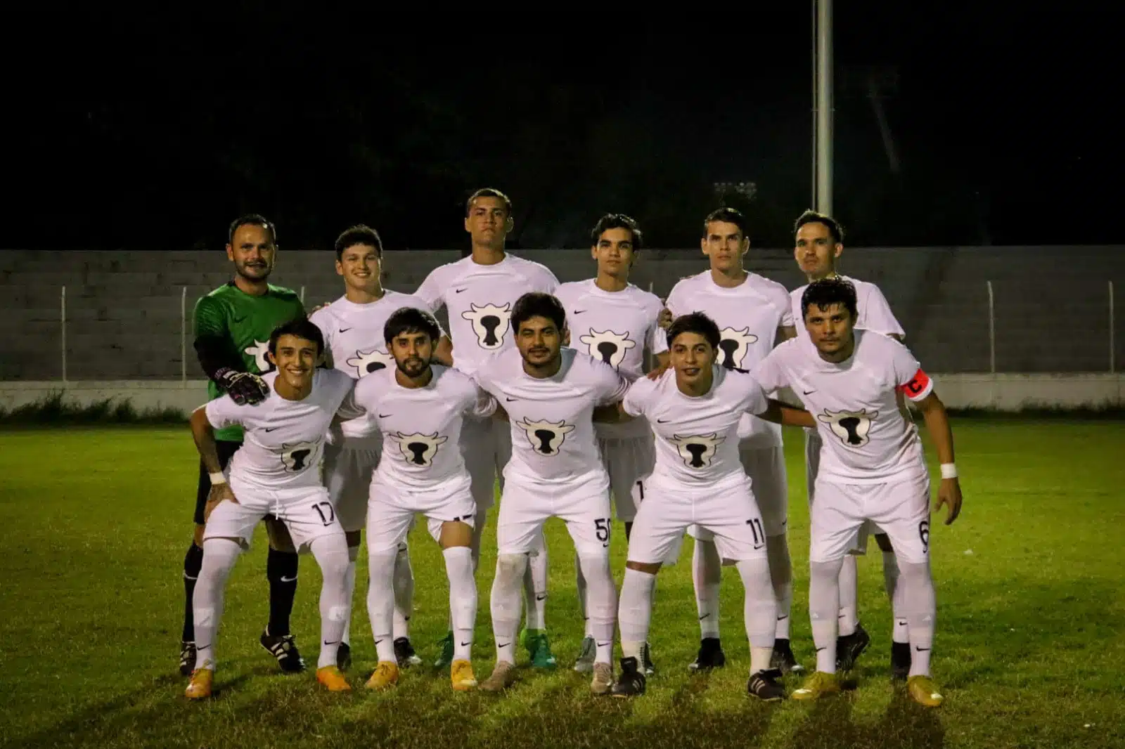 11 personas con uniforme de un equipo de futbol posando para una foto en una cancha en Guasave