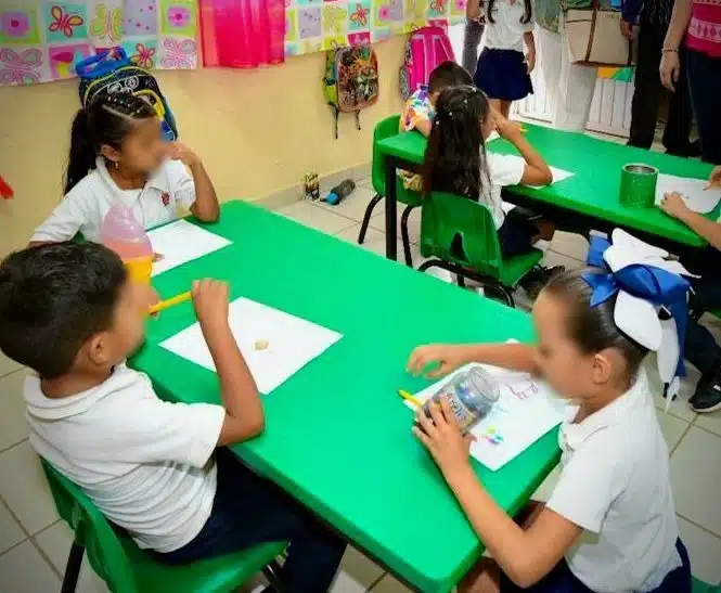 Niños sentados en la mesa de una escuela en Sinaloa
