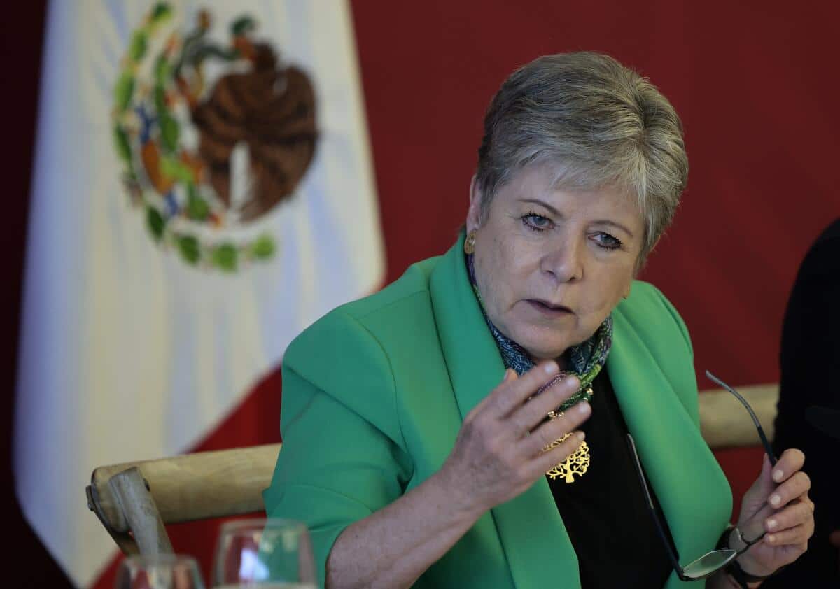 Mujer hablando y atrás bandera de México