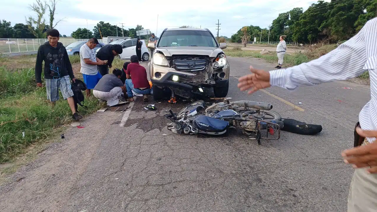 Motocicleta en la calle tras accidente, personas atendiendo a herido